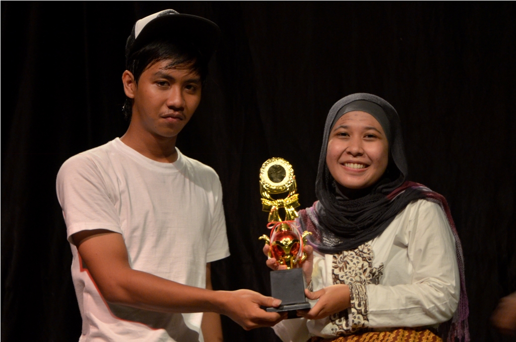 Anggota Teater Gadjah Mada, Ryan (kiri) memberikan piala penghargaan kepada juara pertama dari Fakultas Geografi. Tio Derma