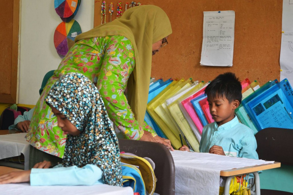 Kepala sekolah MI Giriloyo tampak membimbing siswanya membatik.  Selain menjabat sebagai kepala sekolah, ia juga aktif mengajar batik untuk anak didiknya.