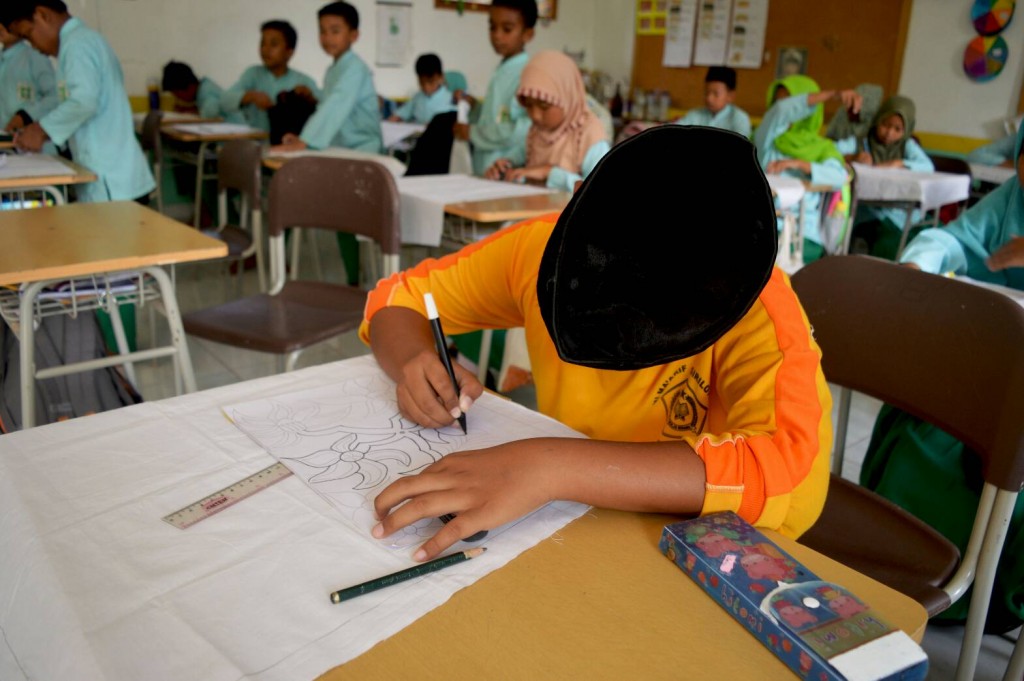 Siswa MI giriloyo sedang menggambar pola batik.  Setiap anak di kelas ekstrakulikuler batik diberi secarik kain mori untuk digambar sesuai kreativitas masing-masing.